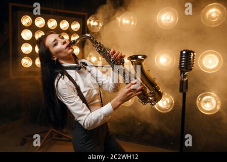 Saxophonistin spielt auf der Bühne mit Scheinwerfern das Saxophon. Jazz-Performer spielt auf der Szene Stockfoto