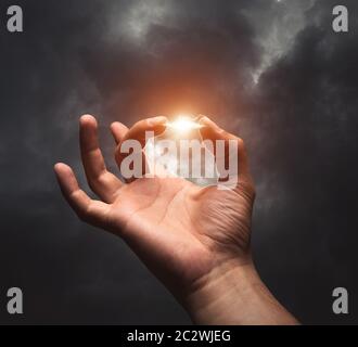 Zwischen zwei Fingern vor einem dunklen Hintergrund Blitze Stockfoto