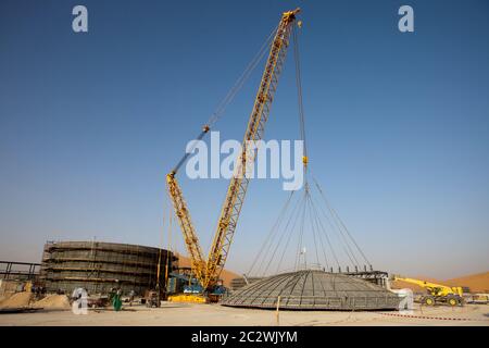 Ein schwerer Hub eines großen Deckels beginnt. Diese wird an der Oberseite eines dahinter liegenden Druckbehälters montiert, der Teil des Baus einer neuen Ölanlage in der Wüste Sahara ist. Stockfoto