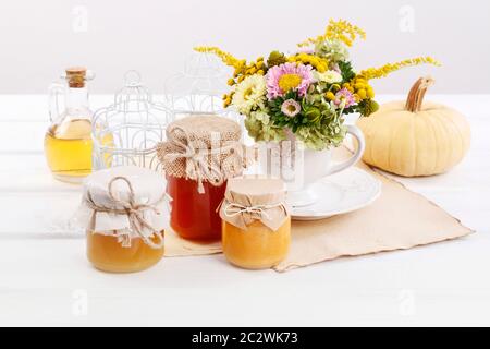 Gläser mit Honig und Strauß von wilden Blumen auf dem Tisch. Gesunde Ernährung Stockfoto