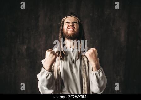 Jesus Christus in ein weißes Gewand betet emotional ballte die Hände zu Fäusten, dunklen Hintergrund. Sohn Gottes, einen starken Glauben an Gott Stockfoto