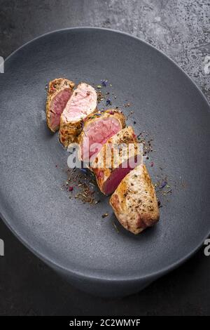 Gebratenes iberisches Schweinefilet in Scheiben geschnitten mit Gewürzen als Nahaufnahme in einer Gusseisen-Design-Platte Stockfoto