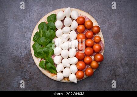 Salami und Gemüse Topping auf Pizza Base über schwarzen Schiefer Stockfoto