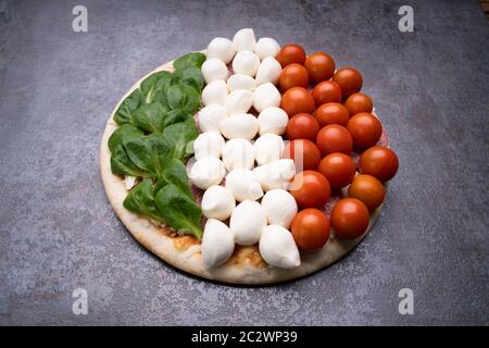 Salami und Gemüse Topping auf Pizza Base über schwarzen Schiefer Stockfoto