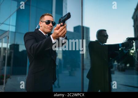 Leibwächter in Anzug und Sonnenbrille mit Sicherheit Hörer und Waffe in seinen Händen. Die Bewachung ist eine riskante Beruf, Politik und Wirtschaft Personen zu schützen Stockfoto