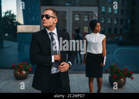 Leibwächter in Anzug und Sonnenbrille, weiblich VIP-Kunde für den Hintergrund. Security Guard ist eine riskante Beruf, professionelle Bewachung, business Personen Protein Stockfoto