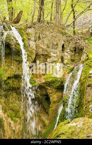 Kleiner Wasserfall zwischen den Felsen mit Moos. Stockfoto