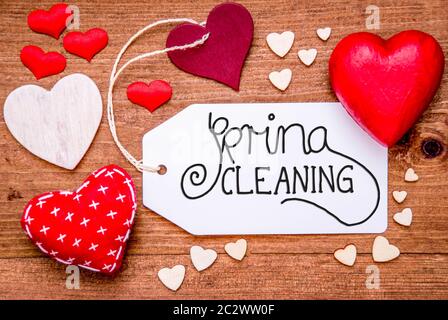 Ein Etikett mit englischen Kalligraphie Frühjahrsputz. Rote Herzen für die Dekoration auf hölzernen Hintergrund Stockfoto