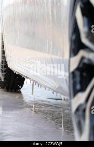 Nahaufnahme des Autos ist mit Schaum bei der Selbstbedienung Autowäsche bedeckt. Ansicht von unten. Stockfoto