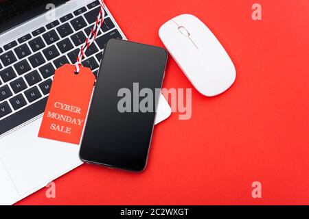 Cyber Monday Verkauf Text auf rotem Tag haben smart phone über Laptop mit rotem Hintergrund Stockfoto