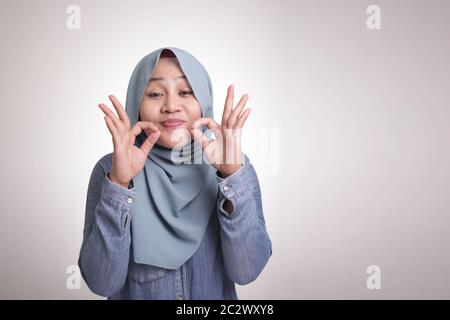 Portrait der schönen asiatischen muslimischen Frau lächelt, während köstliche Hand Geste mit ihren Fingern, isoliert auf weiß Stockfoto