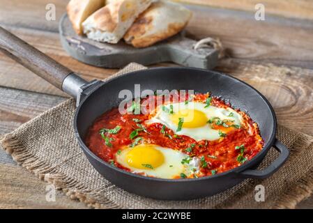 Shakshouka - pochierte Eier in Tomatensauce, in einer Pfanne serviert pan Stockfoto