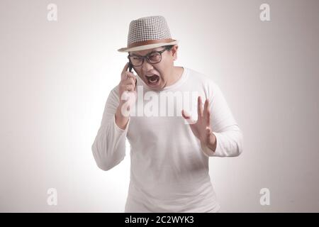 Attraktiver junger asiatischer Mann, der am Telefon spricht, schlechte Nachrichten bekommt, schockierte wütende Geste Stockfoto
