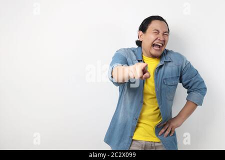 Porträt von lustigen asiatischen Mann lacht hart und zeigt nach vorne, Bully Ausdruck, Nahaufnahme Kopf mit selektivem Fokus Stockfoto