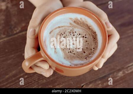 Eine Tasse Kakao mit heißem Geschmack in den Händen. Nahaufnahme. Schöner Milchschaum. Stockfoto