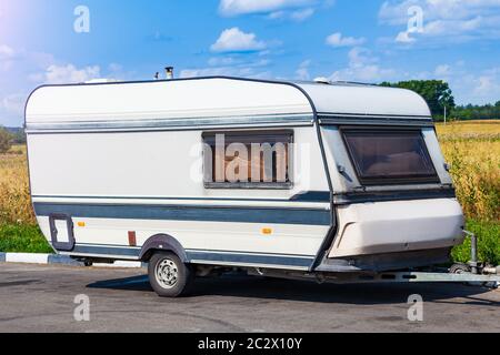 Alte weiße Anhänger van vor dem Hintergrund eines Feldes mit gelben Gras und Bäumen mobilen Wohnmobil für die ganze Familie an einem Sommertag zu reisen. Stockfoto