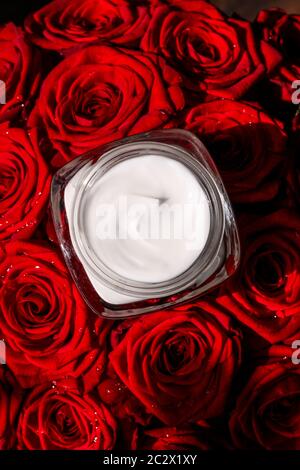 Feuchtigkeitsspendende Beauty Face Creme für empfindliche Haut und rote Rosen Blumen, Luxus-saubere Hautpflege Kosmetik auf floralem Hintergrund Stockfoto