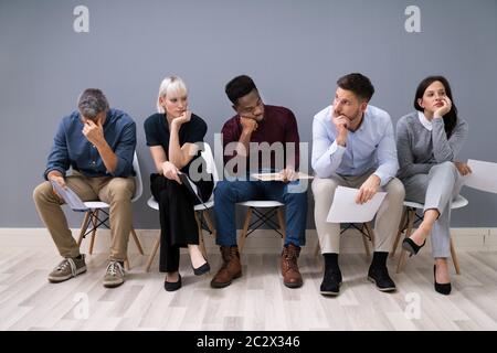 Die Menschen werden immer beim Sitzen auf Stuhl warten auf Job Interview im Büro langweilen Stockfoto