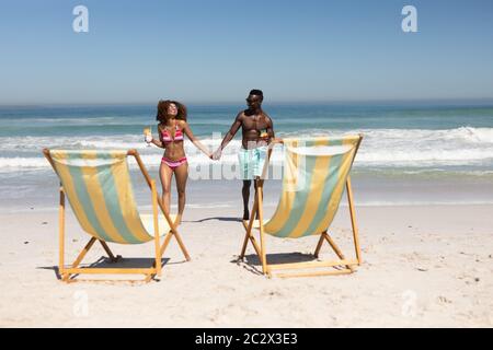Gemischtes Rennpaar hält sich am Strand die Hände Stockfoto