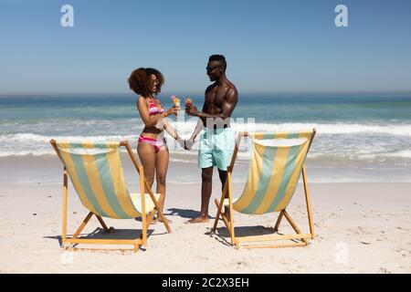 Gemischtes Rennpaar trinkt Cocktails am Strand Stockfoto