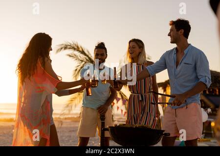 Gemischte Rennfreunde beim Grillen und Alkohol am Strand Stockfoto