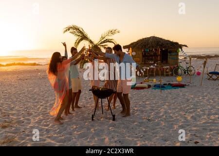 Gemischte Rennfreunde beim Grillen und Alkohol am Strand Stockfoto