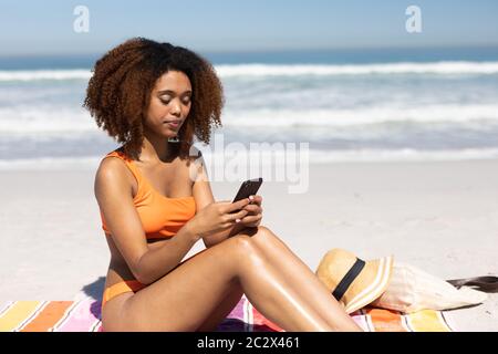 afroamerikanische Frau mit ihrem Smartphone am Strand Stockfoto