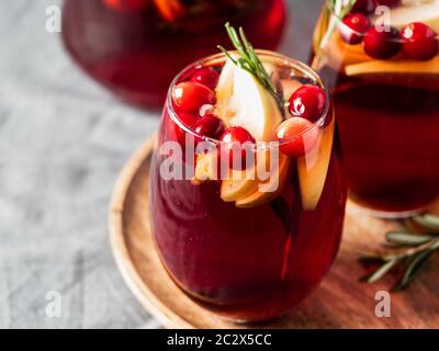 Wintersangria auf Tischplatte mit grauer Leinentischdecke. Gläser Sangria mit Fruchtscheibe, Cranberry und Rosmarin. Platz für Text oder Design kopieren. Hor Stockfoto