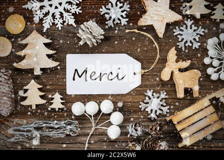 Eine White Label mit französischen Text Merci bedeutet. Vielen Dank. Rahmen von Weihnachten Dekoration wie Baum, Schlitten-, Stern- und Tannenzapfen. Holz- Hintergrund mit Snowf Stockfoto
