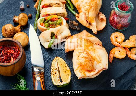 In Scheiben gebackene Tintenfische mit Gemüse auf Schieferplatten. Squid gefüllt mit Pilzen Stockfoto