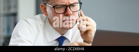 Der Mann spricht am Telefon und zeigt auf den Computerbildschirm Stockfoto