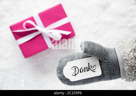 Etikett mit Deutschen Kalligraphie Danke, Danke. Grau Handschuh mit rosa Geschenk und Schnee Hintergrund Stockfoto