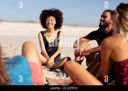 Multiethnische Gruppe von Männern und Frauen, die am Strand sitzen Stockfoto