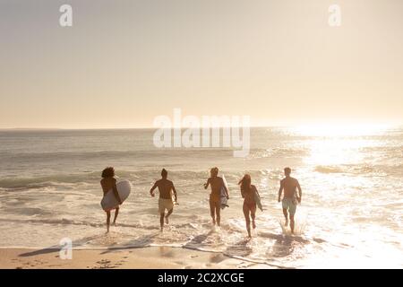 Multiethnische Gruppe von Männern und Frauen, Surfen am Strand Stockfoto