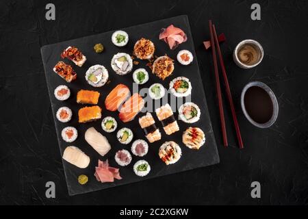 Großes Sushi-Set, von oben auf dunklem Hintergrund mit Essstäbchen, Sake und Sojasauce geschossen. Eine Auswahl an Maki, Nigiri und Stockfoto