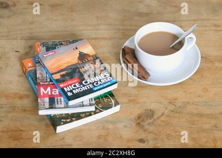 Reisebücher mit einer Tasse Tee in weißer Teetasse auf einem Holztisch Stockfoto