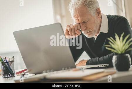 Müde Senior Geschäftsmann reiben seine Augen im Büro sitzen Stockfoto