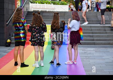 Vier Frauen stehen auf Regenbogenkunstwerken bemalten Boden auf Treppen in Spinningfields Manchester während des PRIDE Wochenendes Stockfoto