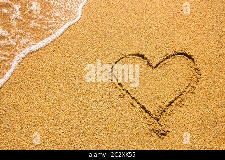 Herz Symbol auf dem Sand. Sommerferienkonzept. Romantische Liebe Hintergrund. Thema Valentinstag. Draufsicht. Herz gezeichnet in Meeresbea Stockfoto
