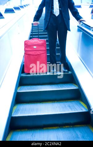 Bildnummer: 192 Datum: April 2005 Modellfreigabe bei Paul Hardy (MR 158) Geschäftsmann mit Koffer, der eine Rolltreppe hinunterfährt. Stockfoto