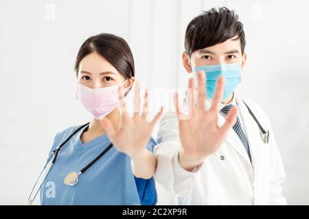 Doktor in Gesichtsmaske und zeigt Stoppschild mit Händen Stockfoto