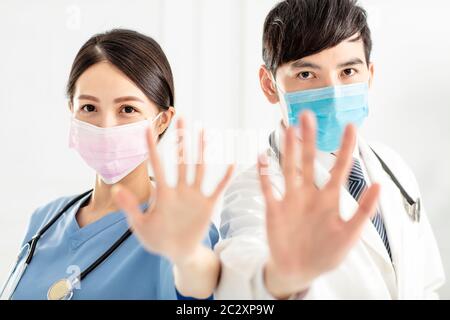 Doktor in Gesichtsmaske und zeigt Stoppschild mit Händen Stockfoto