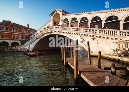 Gondel, die bei Sonnenuntergang unter der Rialtobrücke vorbeifährt, ist die älteste der vier Brücken, die den Canal Grande in Venedig überspannen Stockfoto