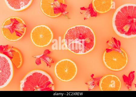 Zitrusfrüchte mit roten Blüten im orangen Hintergrund Stockfoto