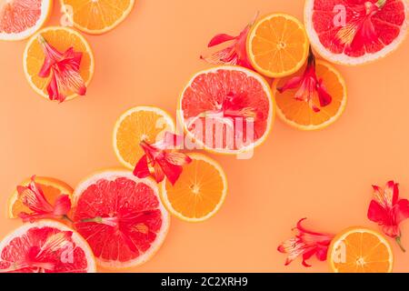 Zitrusfrüchte mit roten Blüten im orangen Hintergrund Stockfoto