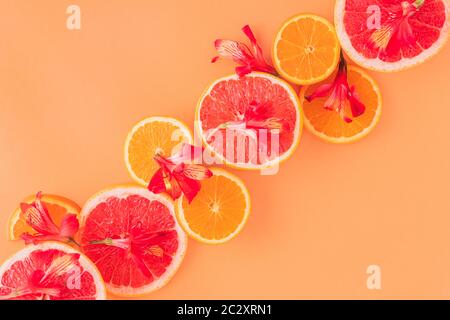 Zitrusfrüchte mit roten Blüten im orangen Hintergrund Stockfoto