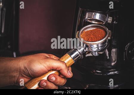 Barista schleifen Kaffee auf Professionelle Kaffeemühle Maschine im Coffeeshop Nahaufnahme. Vorbereitung für Schleifen und Espresso Stockfoto