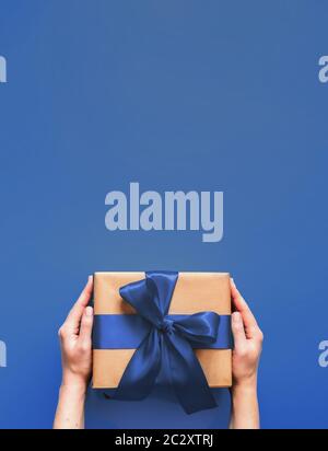 Weibliche Hände halten Geschenkbox auf blau 2020 Farbe Stockfoto