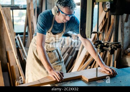 Diligent Carpenter auf der Band sah in seiner Holzwerkstatt Stockfoto