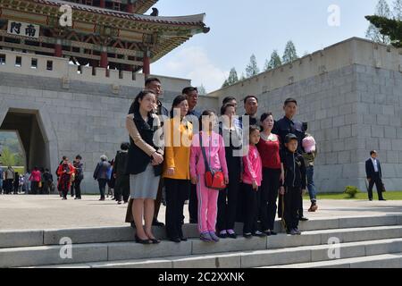 Pjöngjang, Nordkorea - 1. Mai 2019: Menschen entspannen im öffentlichen Park Taesongsan Funfair. Große Familie wird auf der Treppe vor dem ent fotografiert Stockfoto